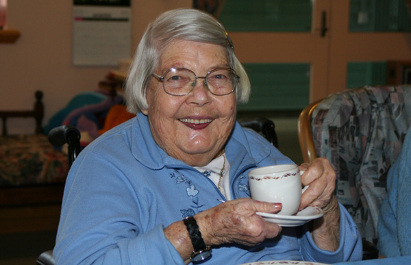 Elderly woman holding a cup of tea and smiling